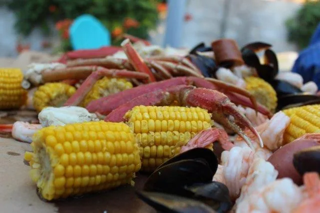 A low-country boil piled on the table: crab clusters, corn on the cob, shrimp and mussels.