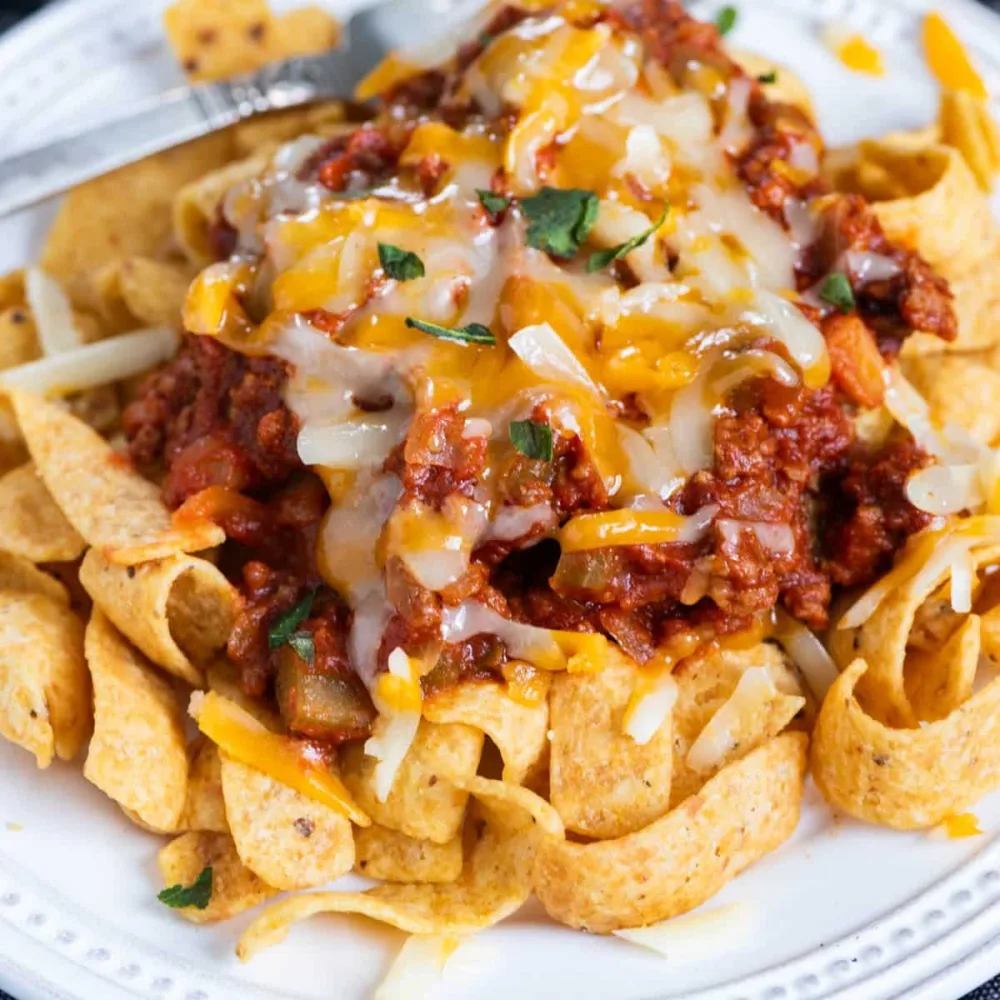 A Frito pie: corn chips under chili with beans, melted cheese and diced onion.