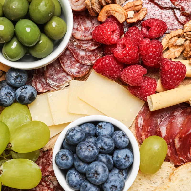 Cheese, fruit, olives and cured meats arranged for grazing.