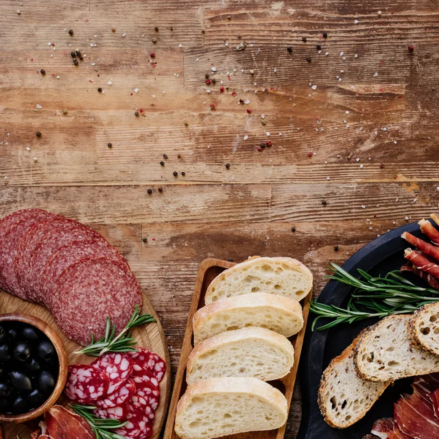 Cured meats, olives and sliced bread on a rustic wooden board.