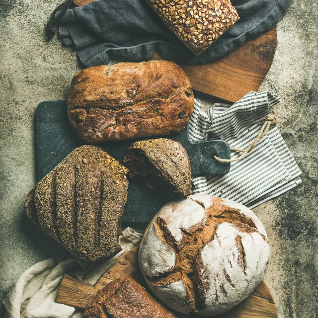 Crusty artisan loaves on cutting boards and linen.