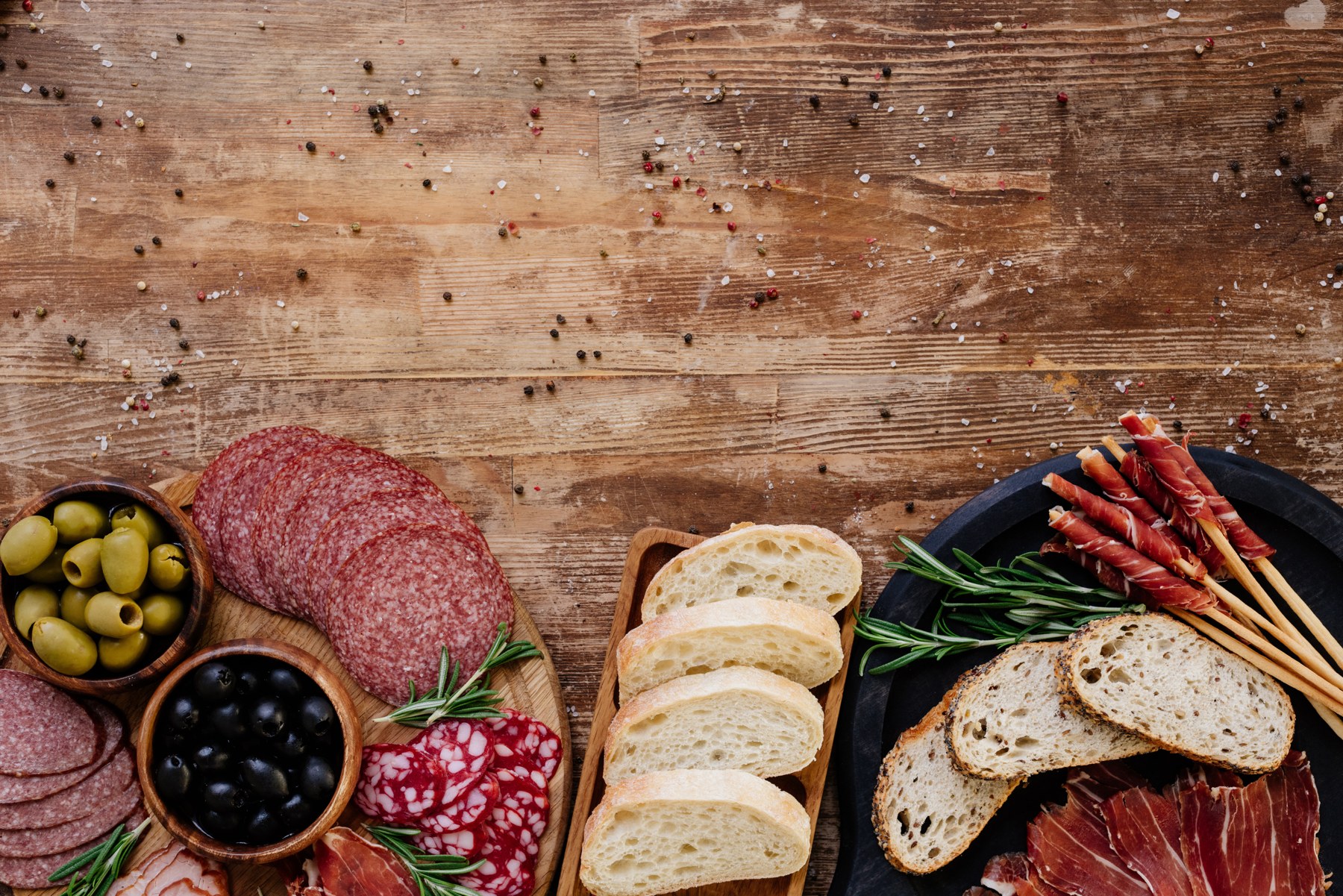 Bread, olives and cured meats arranged for sharing.