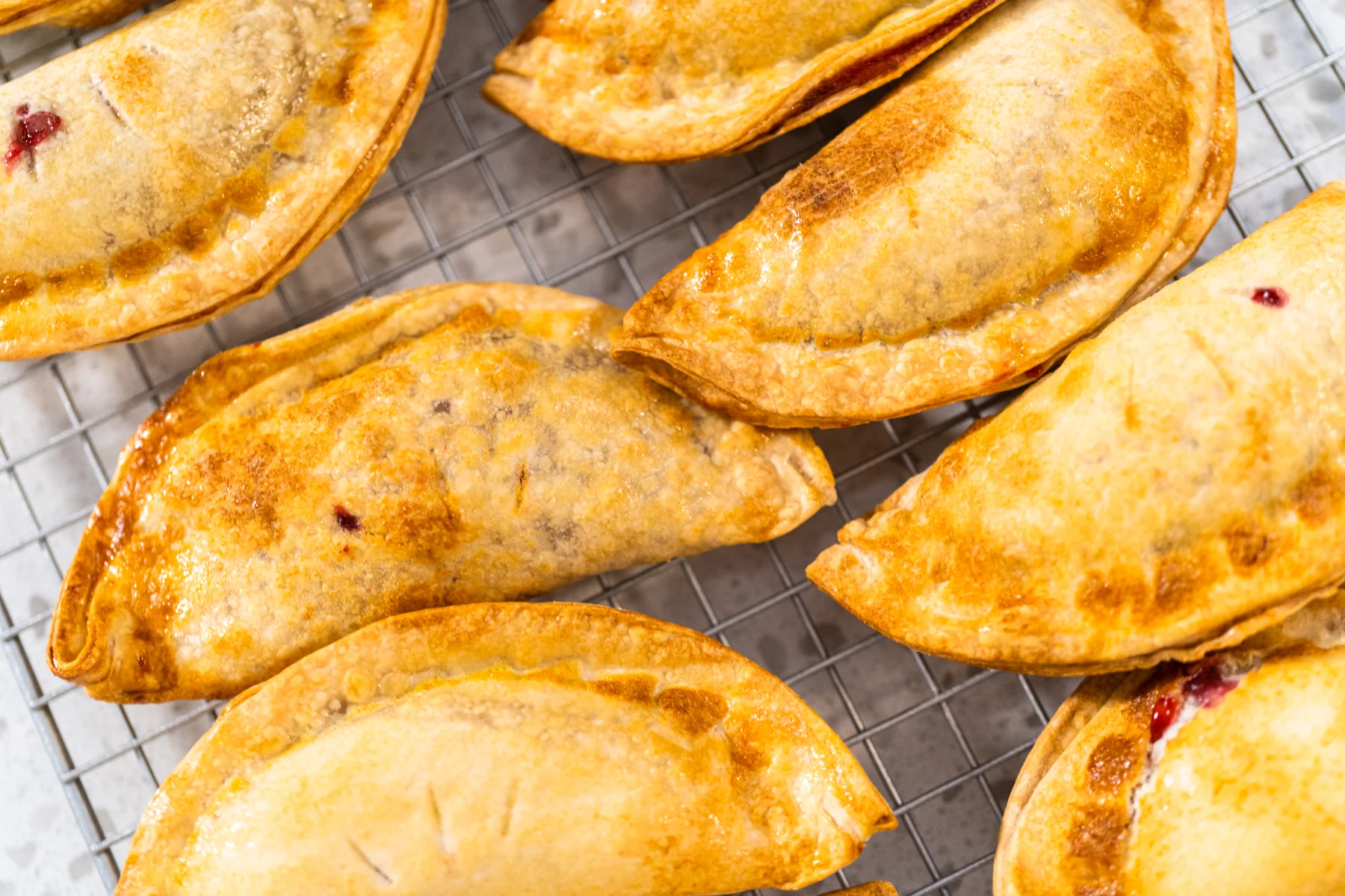 Golden baked fruit empanadas cooling on a wire rack