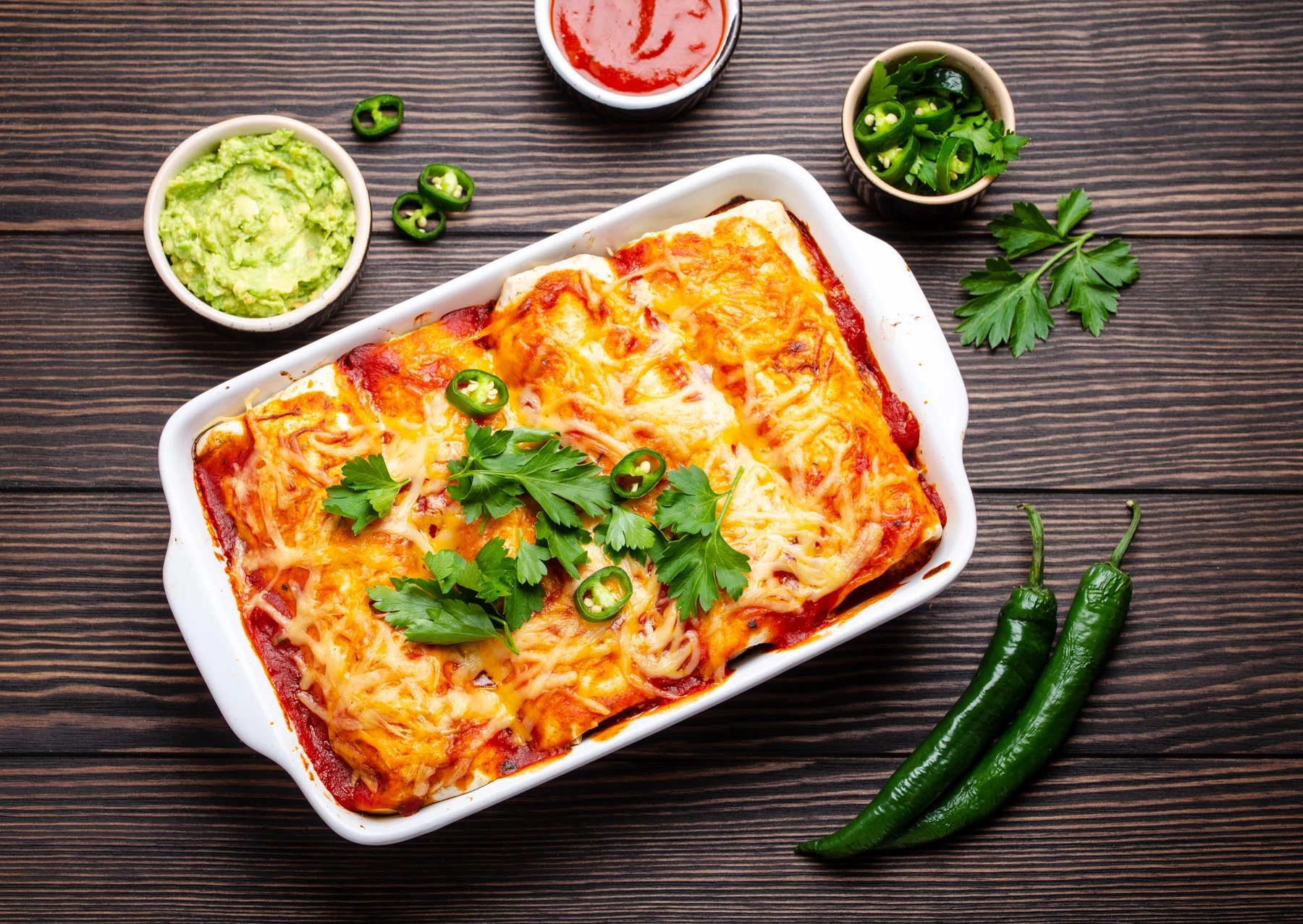 Baked enchiladas topped with melted cheese in a serving dish